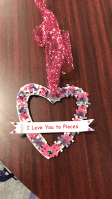 a heart made out of puzzle pieces with a sign that says " i love you to pieces "