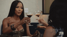 two women are sitting at a table holding martini glasses with bravo written on the screen