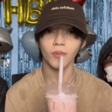 a man wearing a hat with the word dub on it drinks from a plastic cup