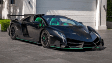 a black and green sports car is parked in front of a white garage