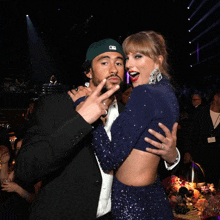 a man wearing a new york yankees hat is giving a peace sign to a woman in a blue dress