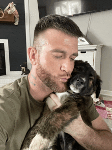 a man with a tattoo on his neck kisses a puppy on the nose