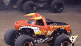 a red el toro loco monster truck is driving on a dirt road
