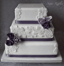 a white wedding cake with purple roses and lace decorations