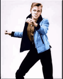 a young man in a blue jacket and black pants is standing in front of a white wall .