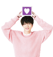 a young man in a pink sweater holds a purple box with a heart on it