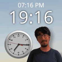 a man stands in front of a wall clock that says 19:16 pm