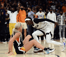 a basketball player with the number 3 on her jersey is helping another player up