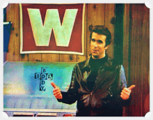 a man is giving a thumbs up in front of a sign that says w