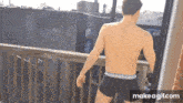 a shirtless man in underwear is standing on a balcony with a pepsi container in the background