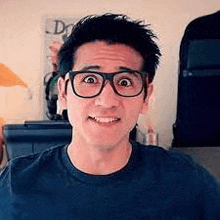 a man wearing glasses is making a funny face while looking at the camera .