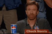 chuck norris is sitting at a table with a cup of pepsi