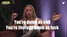 a woman sitting in front of a microphone with the words " you 're dumb as shit " behind her