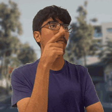 a man wearing glasses and a purple shirt holds his hand to his mouth