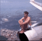 a man is sitting on the wing of a plane .