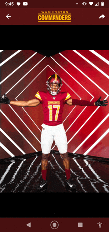 a washington commanders football player stands with his arms outstretched in front of a red background