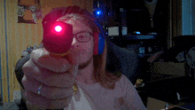 a man wearing headphones and glasses is pointing a gun at the camera