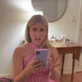 a woman in a pink dress is taking a selfie