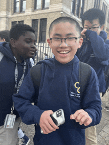 a boy wearing a blue sweatshirt with the letter c on it is smiling