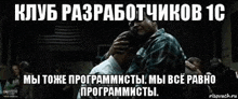 a man is hugging another man in a dark room with russian writing on it .