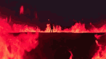 a silhouette of a person standing in front of a large fire .