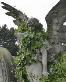 a statue of a woman with wings covered in green ivy