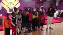 a group of children are standing in front of a purple wall with a logo that says wtc