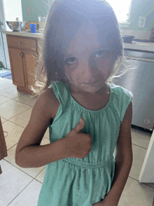 a little girl in a blue dress gives a thumbs up