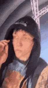 a man wearing a hoodie and headphones is standing in front of a stage .