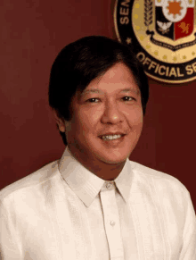 a man in a white shirt is smiling in front of a seal that says official service