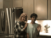 a woman and a boy in front of a samsung refrigerator