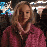 a woman is wearing a pink jacket and sweater
