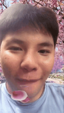 a close up of a man 's face with a flower petal coming out of his mouth