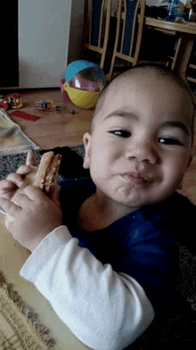 a young boy is eating a sandwich with a beach ball in the background