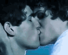 a couple of men are kissing each other in a blue room .