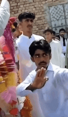 a man with a mustache is making a funny face while standing in front of a crowd .