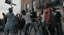 a group of young men are dancing in front of a building that has a sign on it that says ' duke st '