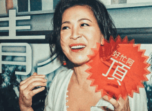 a woman holds up a red sign with chinese characters on it