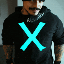 a man is wearing a black shirt with a blue x on the front