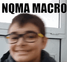 a young boy wearing glasses is smiling in front of a window with the words noma macro above him .