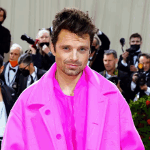 a man in a bright pink coat stands in front of a crowd