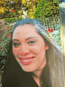 a close up of a woman 's face with a fence behind her