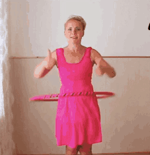 a woman in a pink dress is holding a hula hoop around her waist .