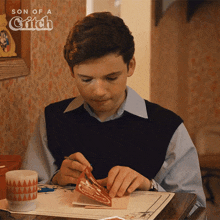 a young man is sitting at a table with a greeting card in front of him that says son of a gitch