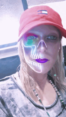 a woman wearing a red tommy hilfiger hat has a skull painted on her face