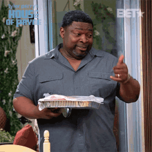 a man in a grey shirt is holding a tray of food in front of a house of payne sign