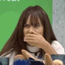 a woman is covering her mouth with her hand while sitting at a table with a bunch of bread .