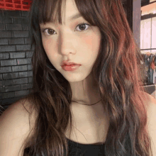 a close up of a girl 's face with a brick wall in the background