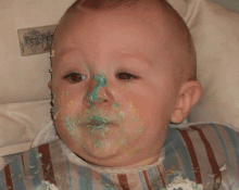 a baby with green frosting on his face is wearing a bib that says peg perego