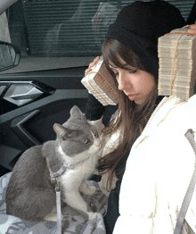 a woman in a car with a stack of money on her head and a cat on her lap